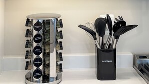 Un armario de cocina con cristalería, platos y un especiero.