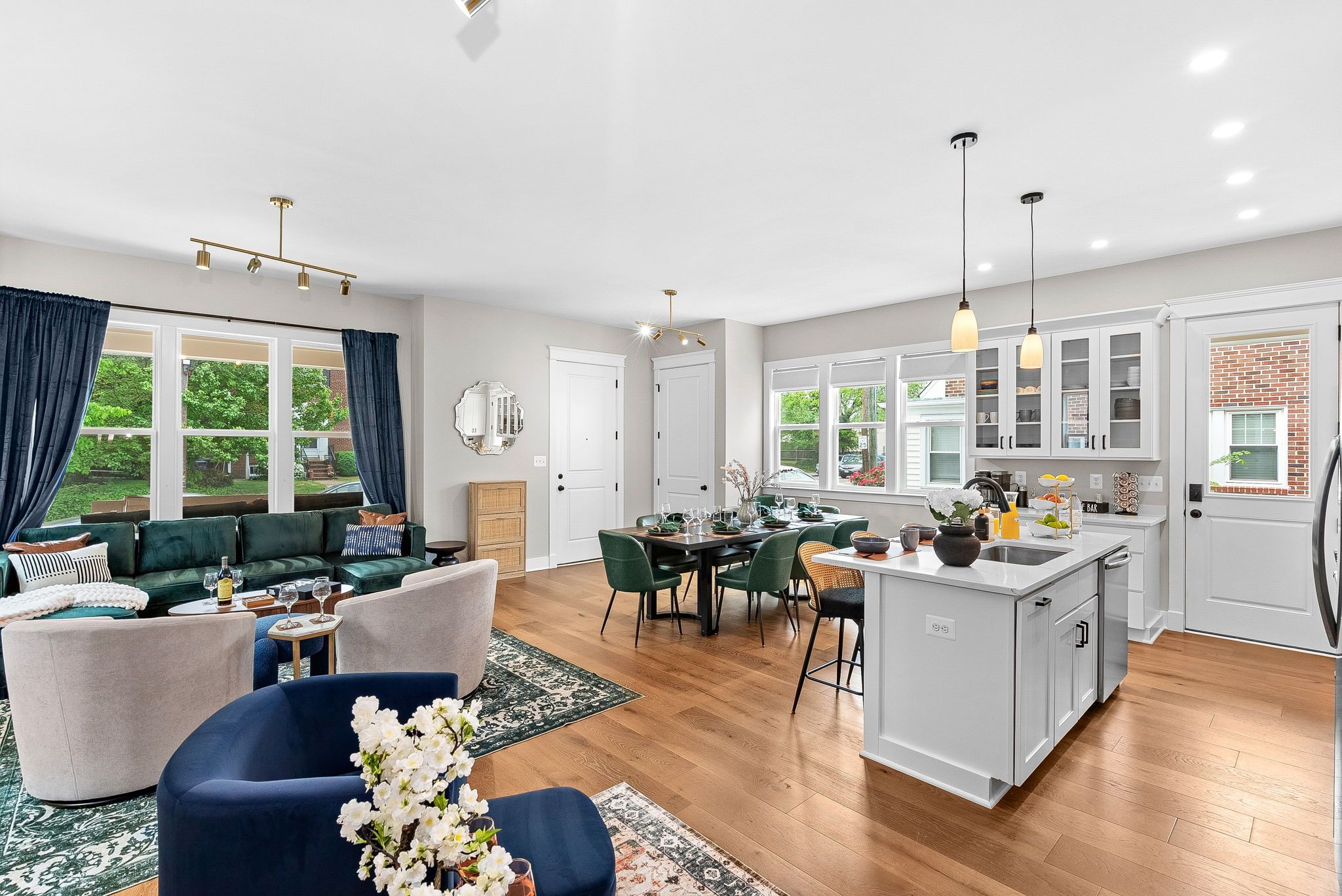 A spacious living area with a dining table, sofas, and a kitchen with a bar.