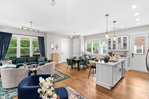 A spacious living area with a dining table, sofas, and a kitchen with a bar. - 7BR Alexandria Retreat, Game Room + Pool Table, Near DC & Old Town (Alexandria)