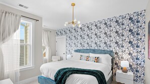 Un dormitorio con cama, mesita de noche y ventana con cortinas.