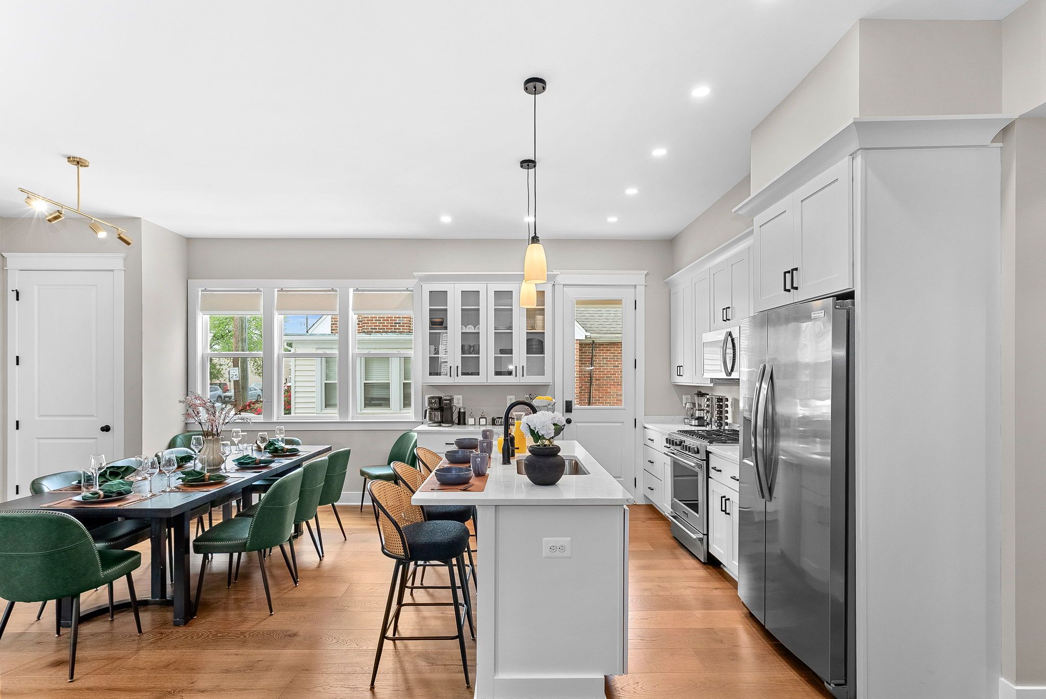 A modern kitchen with a central island, stainless steel appliances, and a dining area with green chairs.