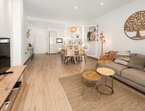 Ein modernes Wohnzimmer mit Sofa, Couchtisch und Essbereich mit Stühlen.