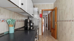 A kitchen with a black countertop, a coffee maker, and a cabinet with a red sign. - La Familia by Interhome (Los Alcázares)