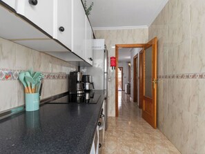 A kitchen with a black countertop, a coffee maker, and a cabinet with a red sign. - La Familia by Interhome (Los Alcázares)
