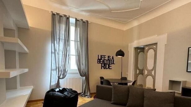 Una sala de estar moderna con un sofá, un sillón de felpa negro y una pared con el texto 'LIFE IS A BEAUTIFUL RIDE'.