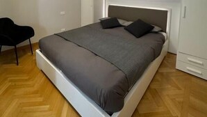 Un dormitorio moderno con cama, una silla y armarios empotrados.