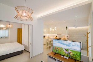 Ein modernes Wohnzimmer mit Bett, Fernseher und Küchenzeile.