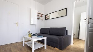 Een moderne woonkamer met een grijze bank, een witte salontafel en een witte deur.