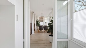 A modern interior with a dining area, large windows, and a potted plant. - Vacation apartment "Waldduft" between the forest and the Baltic Sea beach (Heringsdorf)