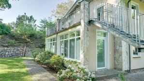 A two-story house with a stone facade, a balcony, and a paved driveway. - Vacation apartment "Waldduft" between the forest and the Baltic Sea beach (Heringsdorf)