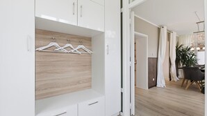 A modern room with a white wardrobe, wooden panel wall, and a dining area with a table and chairs. - Vacation apartment "Waldduft" between the forest and the Baltic Sea beach (Heringsdorf)
