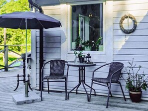 A deck with two chairs, a table, and an umbrella. - 4 Star Holiday Home in Karna (Kärna)