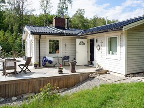 A wooden deck with outdoor furniture, a door, and a window overlooking a natural landscape. - 4 Star Holiday Home in Karna (Kärna)