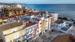 Une zone urbaine côtière avec des immeubles à plusieurs étages, un ciel dégagé et une vue sur la mer.