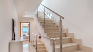 Een moderne trap met metalen leuningen en beige treden, die leidt naar een kamer met uitzicht op de lucht.