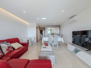 A modern living room with a red sofa, a TV, and a dining area with a white table and chairs. - Colina View by Interhome (Albufeira)