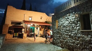 Ein Steinhaus mit rustikalem Äußeren, ein kleiner Laden mit rotem Dach und eine Person davor.