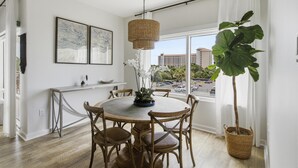Un comedor con una mesa redonda, sillas, una lámpara colgante y una planta grande.