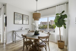 Un comedor con una mesa redonda, sillas, una lámpara colgante y una planta grande.