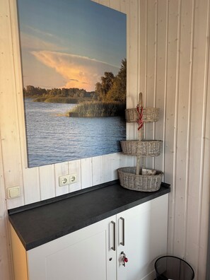 A wall-mounted picture of a lake scene, a black countertop, and three wicker baskets. - Tern 78 (Rechlin)