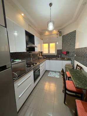 Uma cozinha moderna com armários brancos, fogão a gás, pia e um espaço de refeições com mesa e cadeiras.