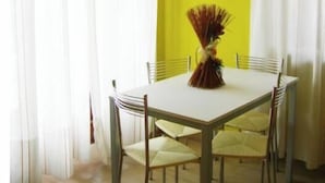 A dining area with a table and chairs, a vase with dried plants, and yellow walls. - Villa Calamita apartment 1 (Capoliveri isola d'Elba)
