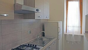 Uma cozinha com fogão a gás, pia de aço inoxidável e armários.