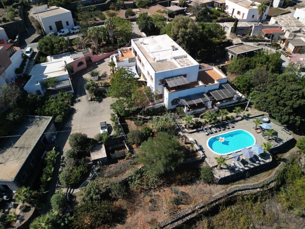 Zona residencial con piscina, varios edificios y abundante vegetación.