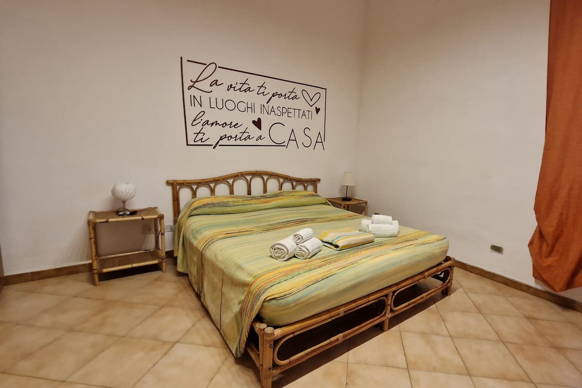 A room with a bed, a bedside table, a lamp, and a wall with a motivational quote.