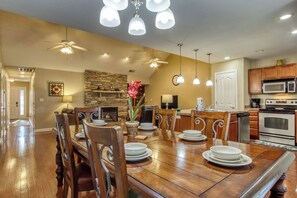 Un comedor amplio con una mesa de madera, sillas y una chimenea de piedra.