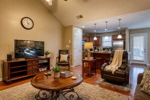 Una sala de estar con televisión, una mesa baja, una silla y un sofá.