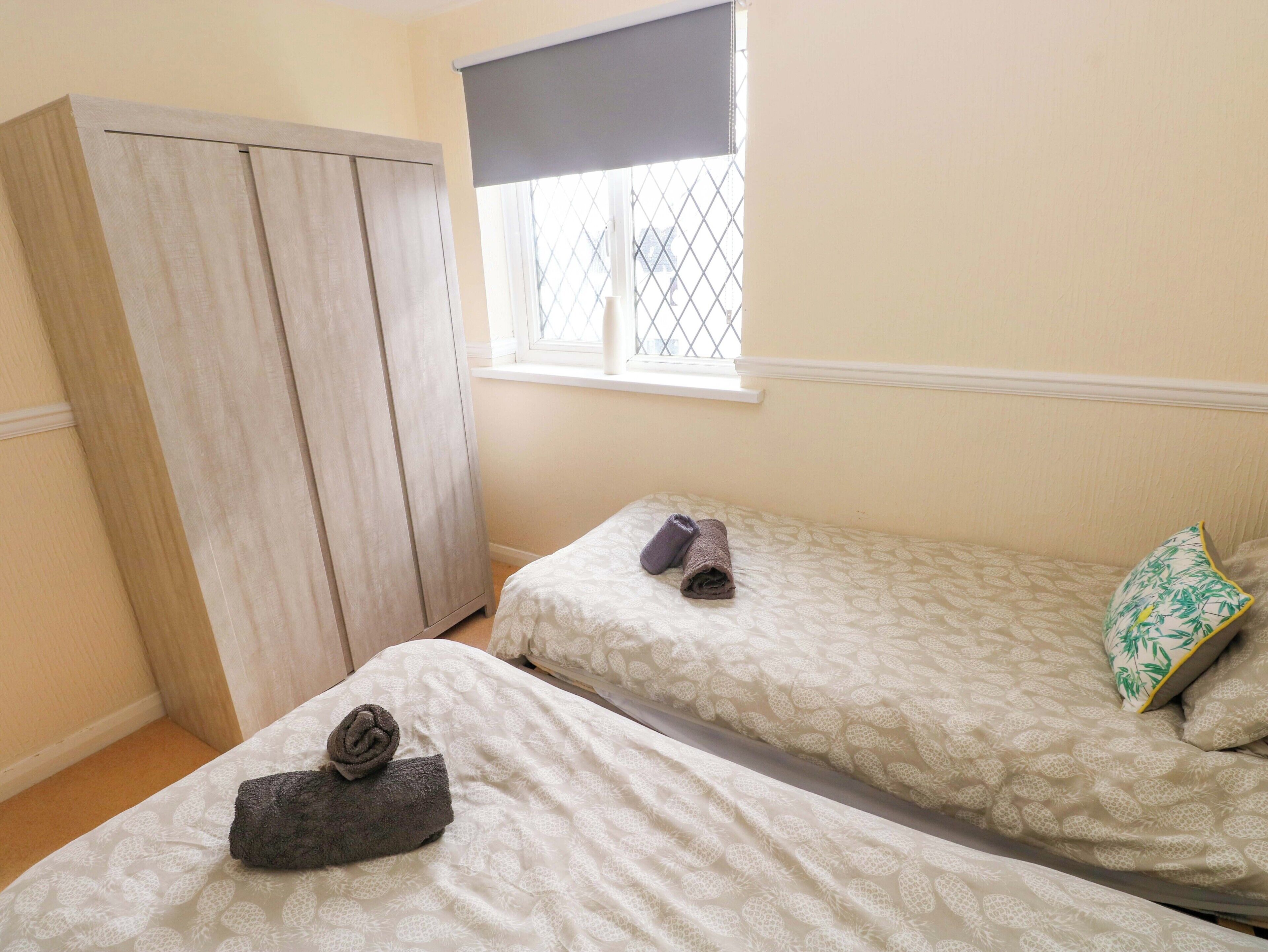 Une chambre avec deux lits, une armoire et une fenêtre avec des stores.