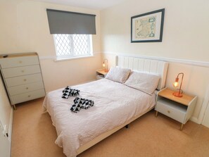 A bedroom with a bed, a nightstand, a dresser, a window with a blind, and a framed map on the wall. - The Wool Pack (Tenby)