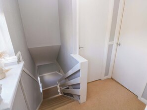 A narrow stairwell with a white door at the top and a white wall on one side. - The Wool Pack (Tenby)