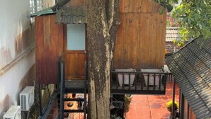 Une maison traditionnelle en bois, avec un toit recouvert de tuiles, une porte en bois et un escalier menant à un balcon.