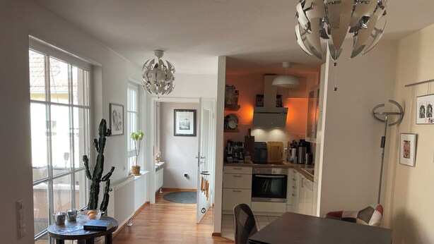 A modern kitchen with a built-in oven, a dining area with a table and chairs, and a hallway leading to a bedroom. - 5+ persons (wheelchair accessible), 2nd floor, Neckargemünd (old town), near Heidelberg (Neckargemünd)