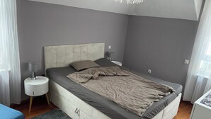 A bedroom with a bed, bedside tables, a lamp, a rug, and a ceiling light fixture. - 5+ persons (wheelchair accessible), 2nd floor, Neckargemünd (old town), near Heidelberg (Neckargemünd)