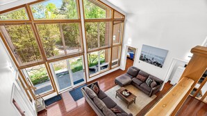 Amplia sala de estar con un gran ventanal corredizo que da a un área exterior, un sofá modular y una mesa de centro.