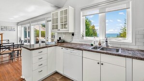 Una cocina moderna con armarios blancos, encimera de granito y lavavajillas.