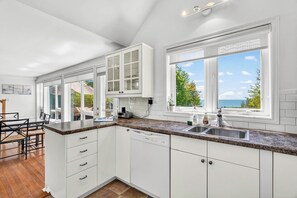 A modern kitchen with white cabinetry, a granite countertop, and a dishwasher.