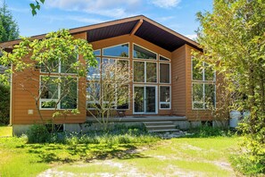 A modern house with large windows, a wooden exterior, and a well-maintained garden.