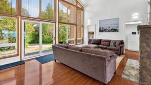 Un salón amplio con ventanas grandes, un sofá marrón y piso de madera.