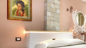 A bedroom with a bed, a dresser, a painting, a stone accent wall, and a mirror.