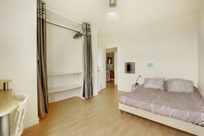 Ein Schlafzimmer mit Bett, Stuhl, Tisch und Kleiderschrank.