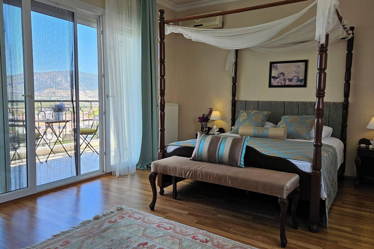 Un lit à baldaquin avec une banquette, une vue sur l’extérieur grâce à une porte coulissante, et une petite table avec une lampe.