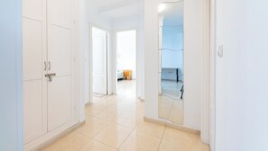 A hallway with white doors, a mirror, and a tiled floor. - Spain Breaks - 2 bed apt With 2 Pools, Airco, Wifi (Benalmádena)