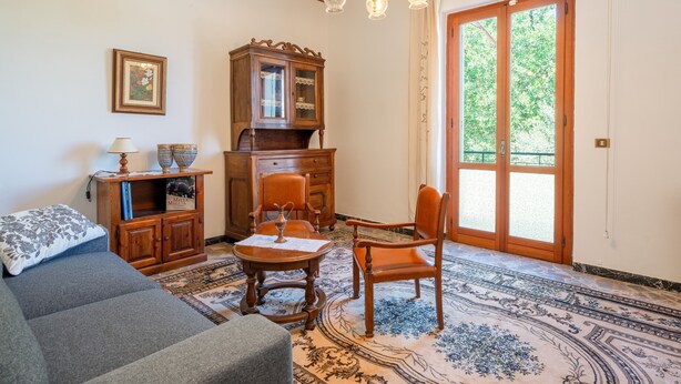 Una habitación con sofá, un aparador de madera, una mesa con un jarrón y una araña.