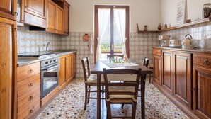 Una cocina con armarios de madera, una estufa, una mesa de comedor con sillas y vistas por una ventana.