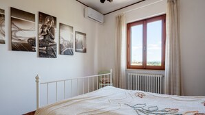 Un dormitorio con cama, radiador, ventana con cortinas y decoración en la pared.
