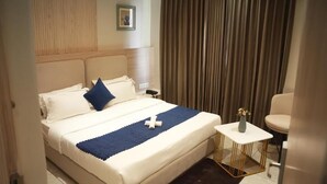 Ein Hotelzimmer mit einem Bett, einem Nachttisch, einem Sessel und einem Vorhang.